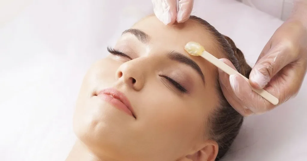 Woman receiving professional face waxing treatment for delicate upper lip or brow area.